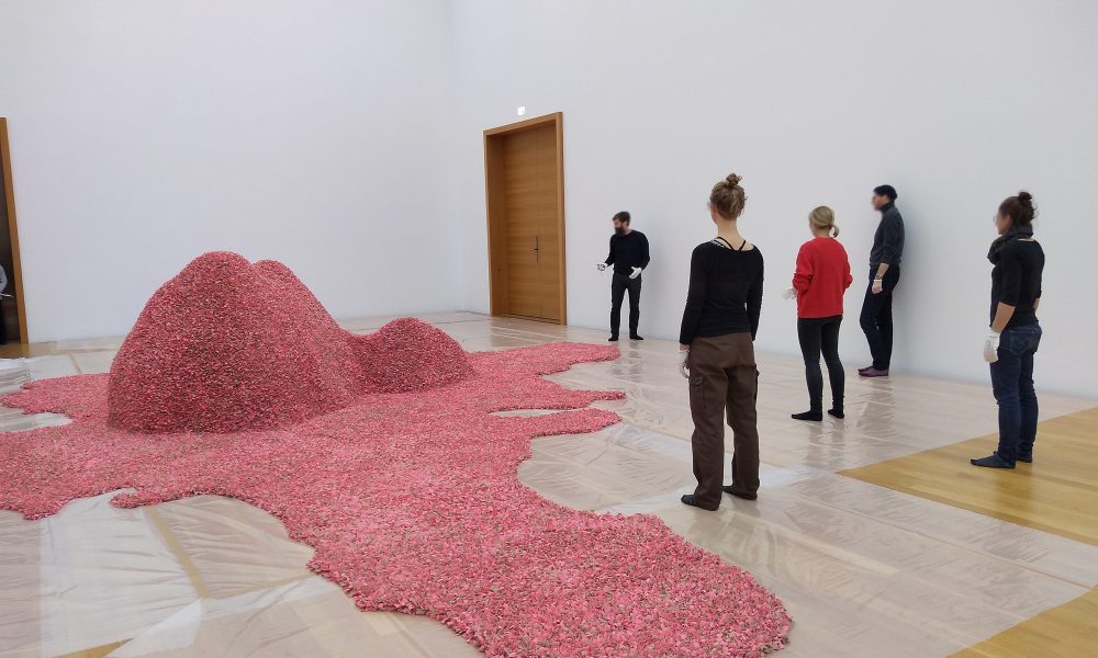 Menschen stehen um eine große pinkfarbene Skulptur in einer Kunstgalerie.