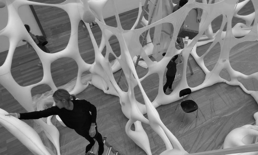 Ein Schwarz-Weiß-Foto einer weißen Skulptur, die auf einem neutralen Hintergrund abgebildet ist.