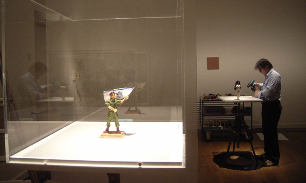 Ein Mann steht vor einem Vitrinenschrank und betrachtet die darin ausgestellten Objekte.