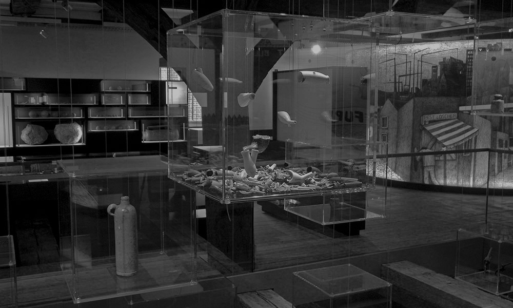 Schwarz-weiß Foto eines Museums mit einem Glaskasten im Vordergrund.